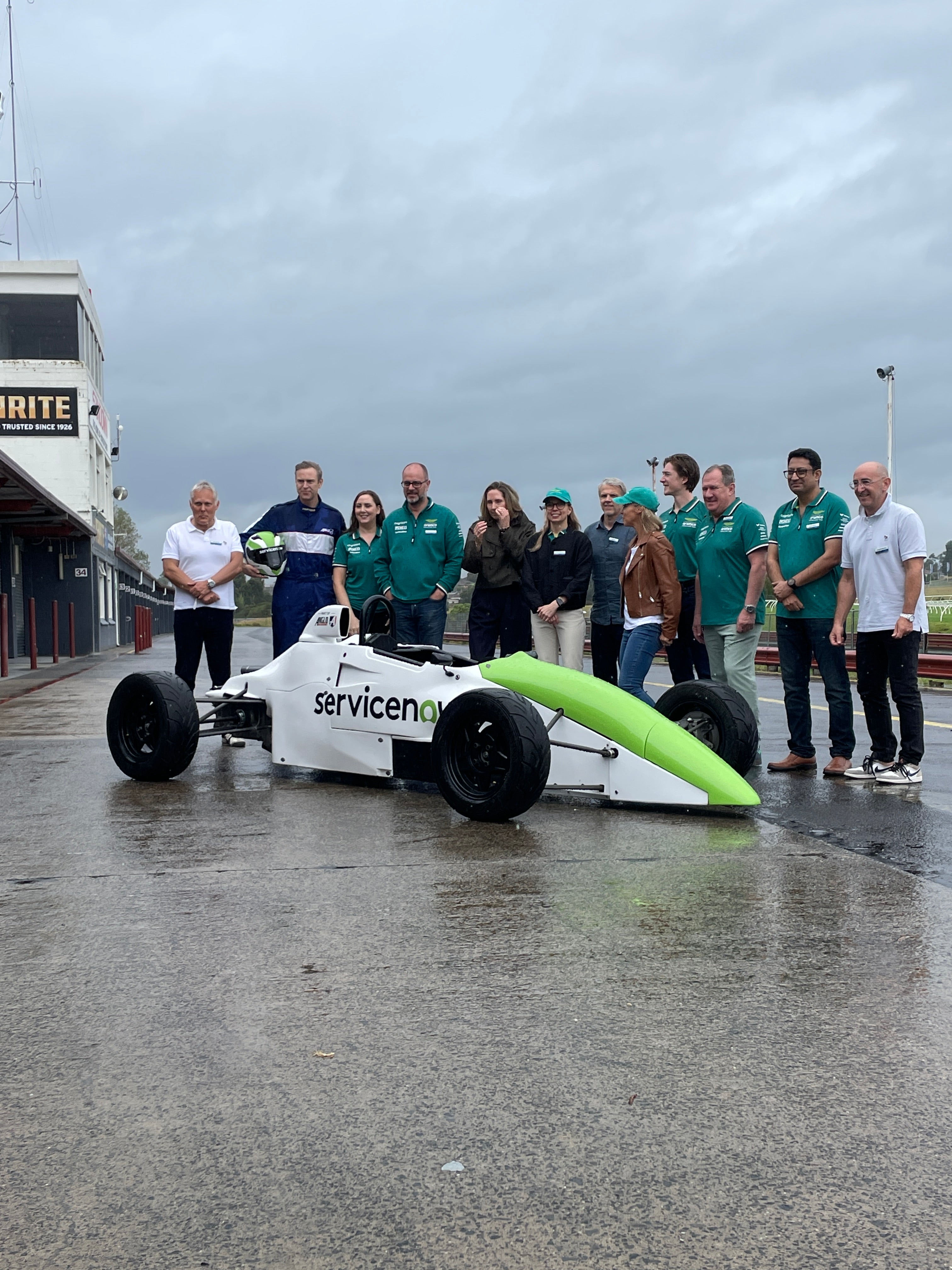 Corporate Group shot of participants around a branded F1-Style Race Car at Sandown Raceway, VIC